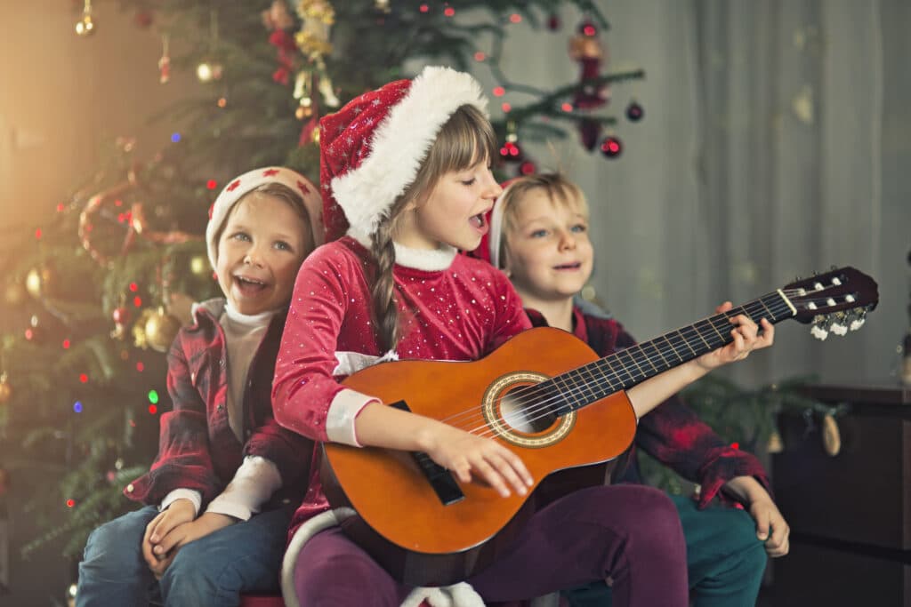 kids singing carols near the christmas tree